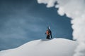 Mountaineer walking up along a snowy mountain with the skis in the backpack. Skier on the climbing track for freeride-descent.