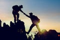 Mountaineering couple helping each other climb up the mountain at sunrise Royalty Free Stock Photo