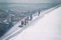 Mountaineers climb a snowy mountain against the background of dark clouds