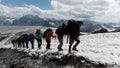 Mountaineers walking up a hill along a snowy slope near camp base. Clip. Western Alps, Europe exploring world through Royalty Free Stock Photo