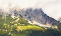 Mountains in the alps with cloudy hillsides, alp and chalet