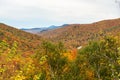 Mountains covered with deciduous forest at the peak of autumn colours and cloudy sky