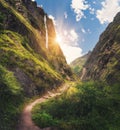 Mountains covered green grass, high waterfall at sunset