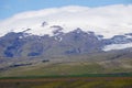 Mountains covered with snow in Iceland, field on first plan