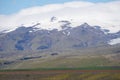 Mountains covered with snow in Iceland, field on first plan