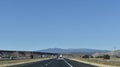 Mountains in the Distance as a Desert Highway Passes Through a Red Rock Valley on a Clear Fall Day Royalty Free Stock Photo