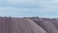 Mountains of empty ore when mining potassium on cloudy sky background. Transportation of an empty rock to a dump. Royalty Free Stock Photo