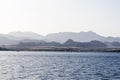 Mountains in the fog on the beach. View from the water. Summer landscape with sea and mountain range Royalty Free Stock Photo