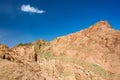 Mountains and hills of red layered rocks with green patches on clear day