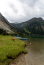 mountains lake in austrian alps with boats on it and red bench in front Royalty Free Stock Photo