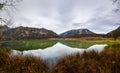 mountains and lake with beautiful reflection with grass on the shore panorama