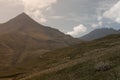 Mountains landscape - mountain peak of pyramid shape in autumn sunny day with white fluffy clouds in soft mist blue sky,