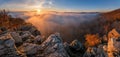 Mountains in low clouds at sunrise in autumn. View of mountain peaks, rocks and red trees in fog in fall. Royalty Free Stock Photo