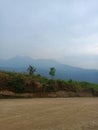 Mountains with misty green skies with green trees and dusty ground