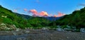 Mountains, over which beautiful clouds float, painted in yellow and orange colors by the rays of the setting sun Royalty Free Stock Photo