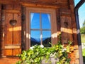 Mountains reflected in an alpine wooden house window Royalty Free Stock Photo