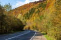 Among the mountains, on the side of a deserted asphalt road, there is a parked car.