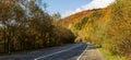 Among the mountains, on the side of a deserted asphalt road, there is a parked car.