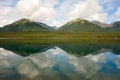 Mountains and trees reflected in a calm lake along the cassiar highway