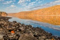 Mountains of vibrant fall foliage is seen from the rocky shore Royalty Free Stock Photo