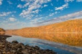 Mountains of vibrant fall foliage is seen from the rocky shore Royalty Free Stock Photo