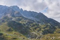 Mountainside with green ledges, and above it an impregnable rocky peak