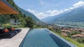 Mountaintop infinity pool with lounge chairs, overlooking valley town Royalty Free Stock Photo