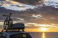 Mounted bicycle silhouette on the car roof with rising sun background. Dramatic sky at mediterranean sea dawn Royalty Free Stock Photo