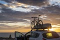 Mounted bicycle silhouette on the car roof with rising sun background. Dramatic sky at mediterranean sea dawn Royalty Free Stock Photo