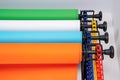 Mounted manual backdrop support system with cross bars and four rolls of colorful paper backgrounds for photo studio hangs on wall