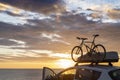 Mounted bicycle silhouette on the car roof with rising sun background. Dramatic sky at mediterranean sea dawn Royalty Free Stock Photo