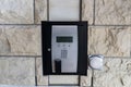 Mounted on a stone wall, an entrance security system features a keypad, display screen, and an intercom. The system provides Royalty Free Stock Photo