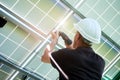 Mounter wearing white helmet working with drill installing solar panels. Royalty Free Stock Photo