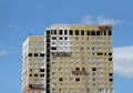 Process of mounting insulation on apartment building facade in new modern urban house over blue sky with clouds front view Royalty Free Stock Photo