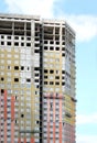 Process of mounting insulation on apartment building facade in new modern urban house over blue sky with clouds front view Royalty Free Stock Photo