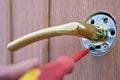 Mounting lever door handle, locksmith tightens screw with screwdriver.