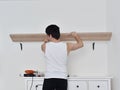 Mounting shelves on the wall. All necessary tools are placed on the chest of drawers