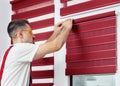 Mounting shutters, man installing fabric blinds. Handyman installing a part of roller window blind indoors. Construction Royalty Free Stock Photo