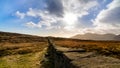 Mourn Wall on the bank of Slieve Donard mountain with blue sky, white clouds and sunrays