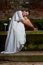 Mourning woman white dress sitting stone bench