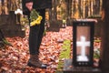 Mourning woman holding flowers in hands and standing at grave in cemetery Royalty Free Stock Photo