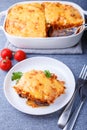 Moussaka with meat, eggplant, tomatoes, potatoes, bechamel sauce and cheese on a white plate. Traditional Greek dish. Close-up. Royalty Free Stock Photo