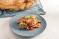 Moussaka served with parsley garnish on a blue gray plate on a white table, traditional Greek casserole of eggplants, potatoes, Royalty Free Stock Photo