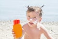 Moustaches cat drawing sunscreen (suntan lotion) on hipster boy face before tanning. Royalty Free Stock Photo