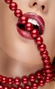 Mouth with red lipstick biting red pearls Royalty Free Stock Photo