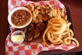 Mouth watering image of fried clams, onion rings, sea scallops and baked beans on table at restaurant