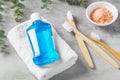 Mouthwash on white towel with toothbrush and pink salt on grey table Royalty Free Stock Photo