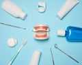 Mouthwash, toothpaste tube, dental floss and medical mirror on a blue background, oral hygiene