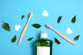 Mouthwash, two wooden bamboo eco friendly toothbrushes, green leaf, white hearts on blue background. Teeth hygiene.