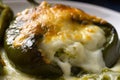 Mouthwatering close-up of a cheesy Chiles Rellenos oozing with melted cheese and drizzled with tangy salsa verde